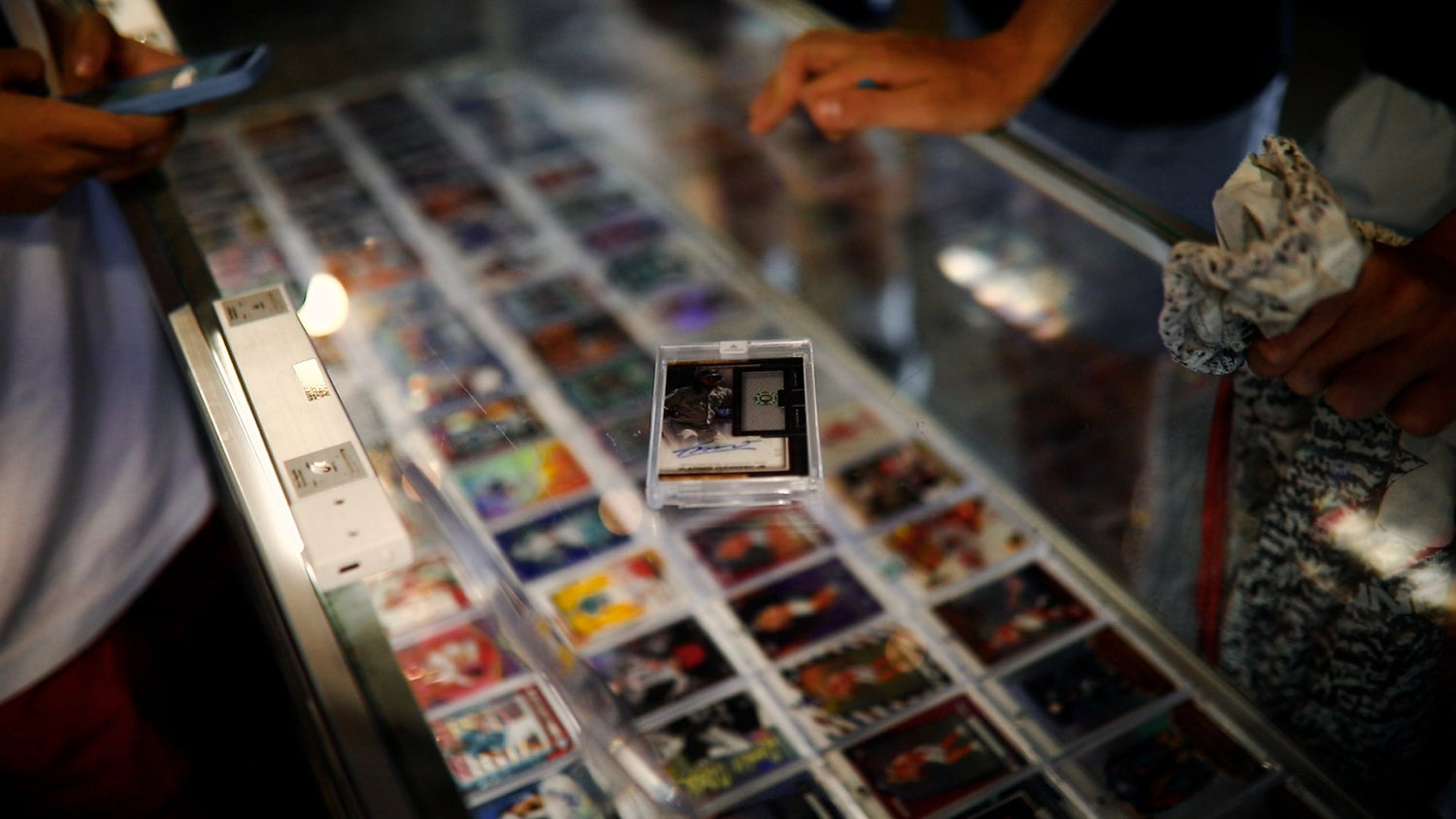 Collection of trading cards displayed in a glass case with people around
